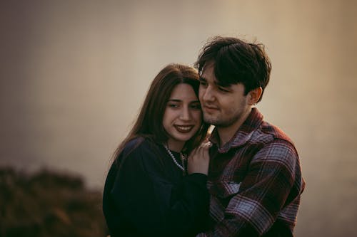 A Young Couple Standing Outside Hugging and Smiling 