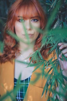 一幅绿叶环绕的红发女子特写肖像，充满活力与自然气息