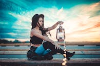 日落时分，一位戴着帽子的时尚女士手持灯笼，营造出梦幻般的氛围