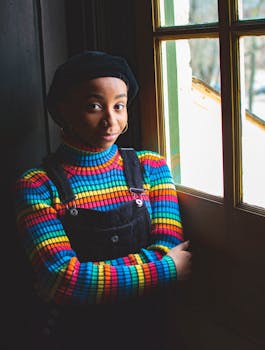 窗前站着一位穿着彩色毛衣的开朗女子，她笑容满面