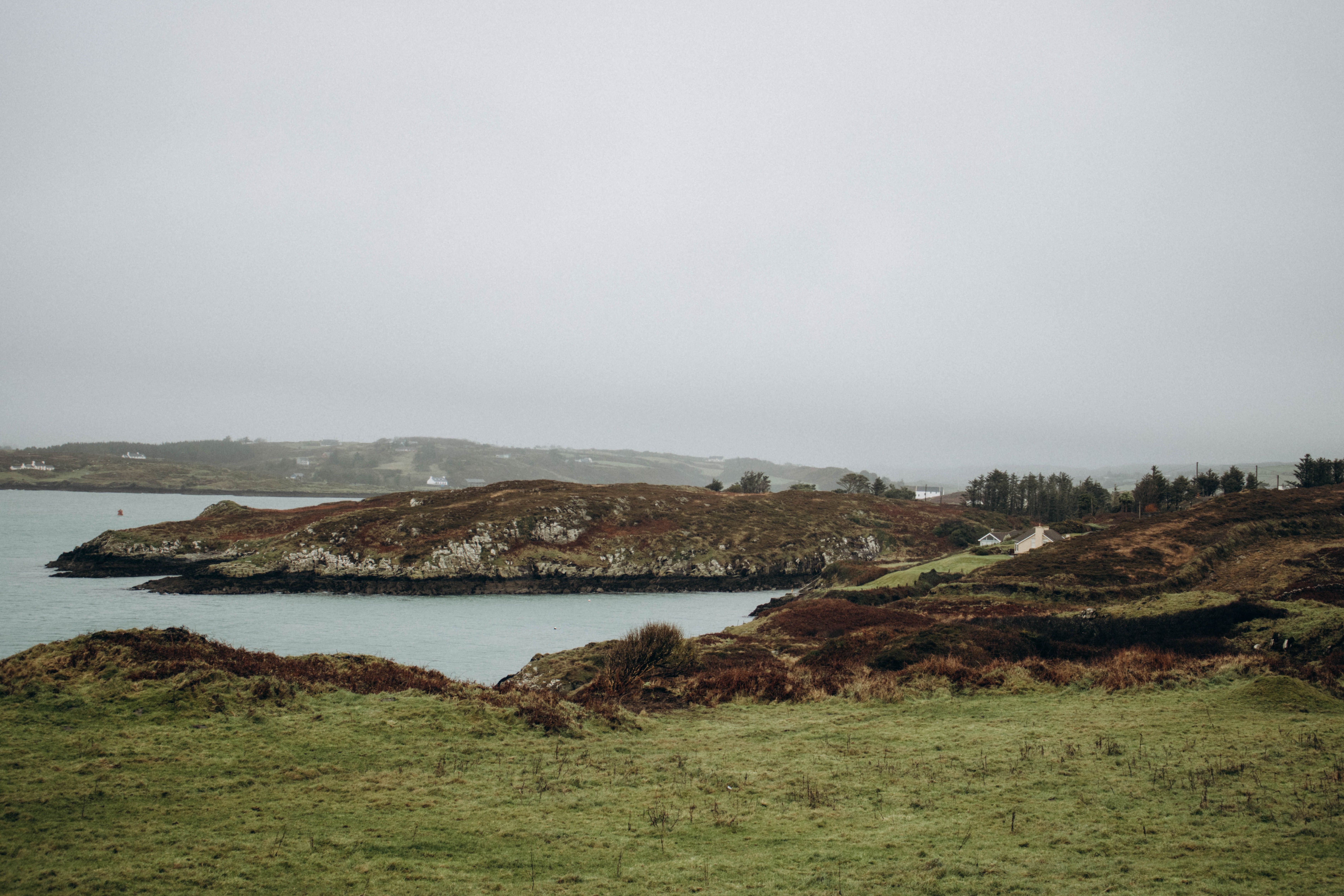 A serene autumn landscape featuring a rocky shoreline and calm waters under an overcast sky.
