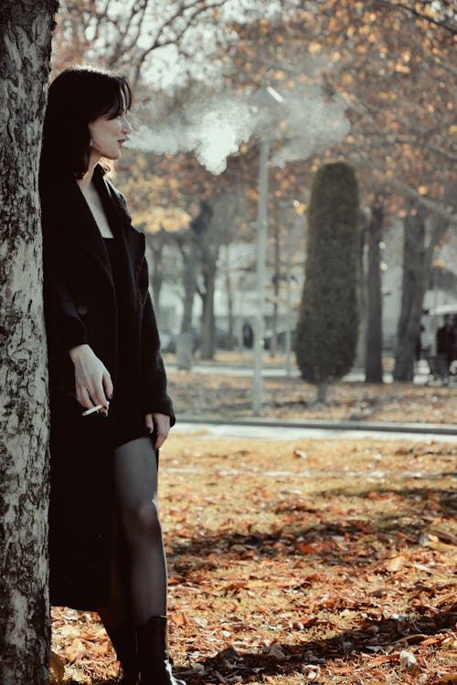 Brunette Woman in Black Coat with Cigarette in Hand