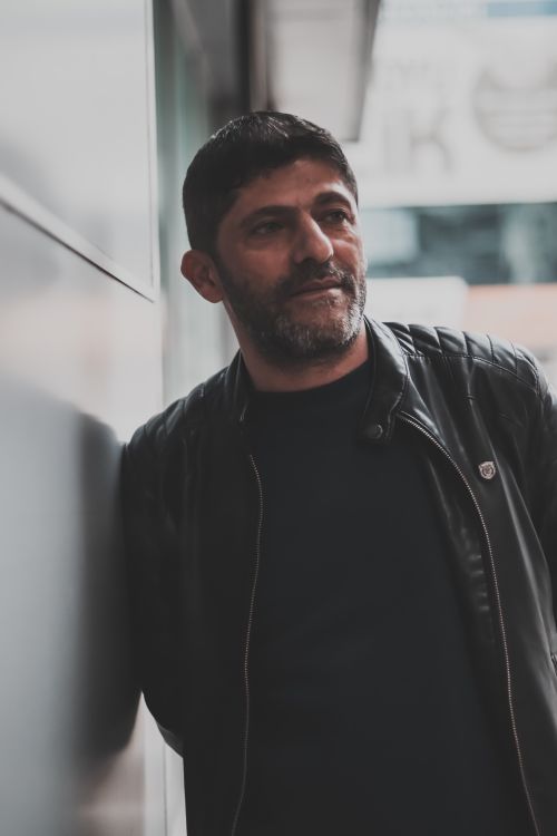 Free Middle-aged man in leather jacket leaning against a wall in an urban setting. Fashionable and moody portrait. Stock Photo