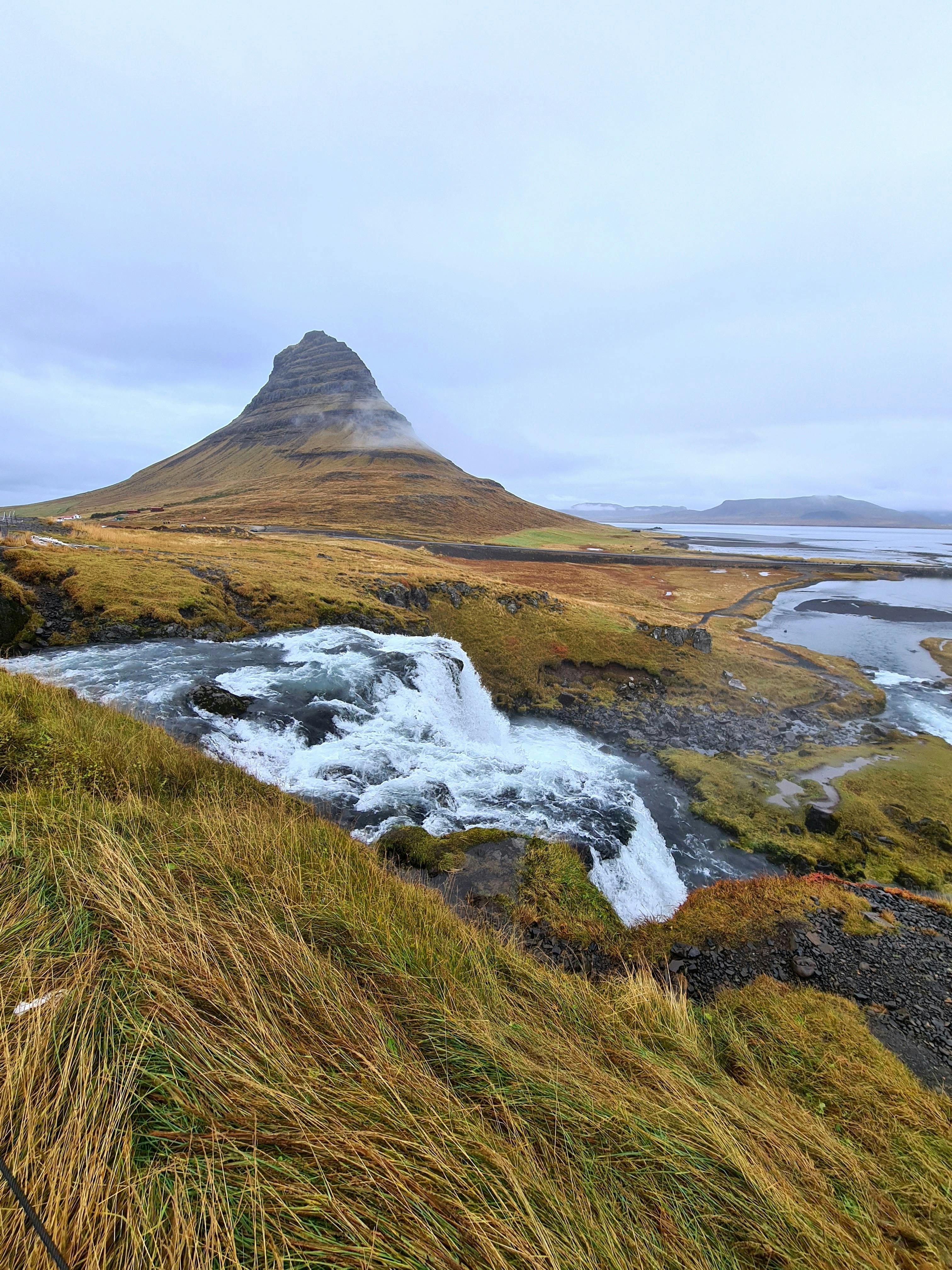 Scenic view of Kirkjufell mountain with cascading waterfall in Icelandic winter landscape.