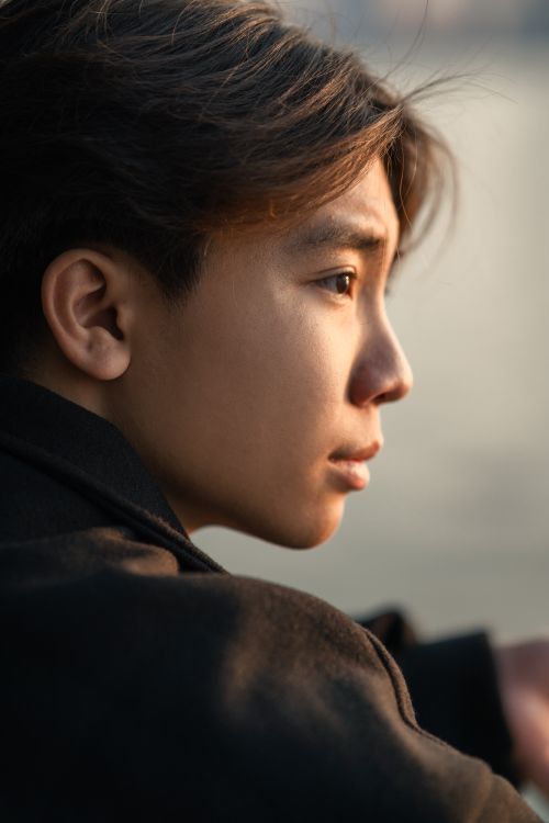 Contemplative Man by Waterfront Bridge at Sunset · Free Stock Photo