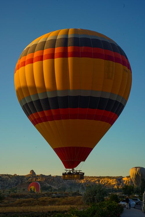Free Vibrant hot air balloon soaring over Cappadocia's unique landscapes in Türkiye during a sunny day. Stock Photo