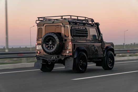 A rugged SUV with a spare tire travels on an Erbil highway at sunset, showcasing adventure vibes.