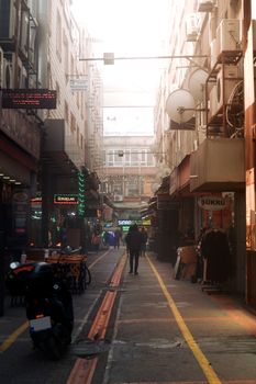 A bustling alleyway in Sakarya, Türkiye, with shops and people in the early morning light.