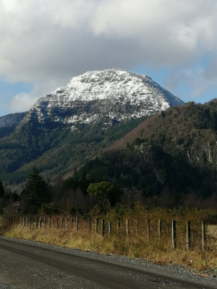 Snow Covered Mountain Overlooking A Dirt Road