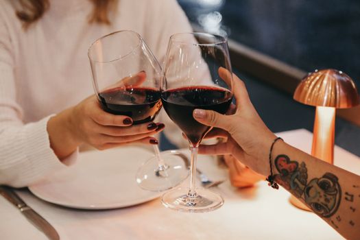 Friends clinking red wine glasses at a cozy dinner setting, embracing relaxation and enjoyment.