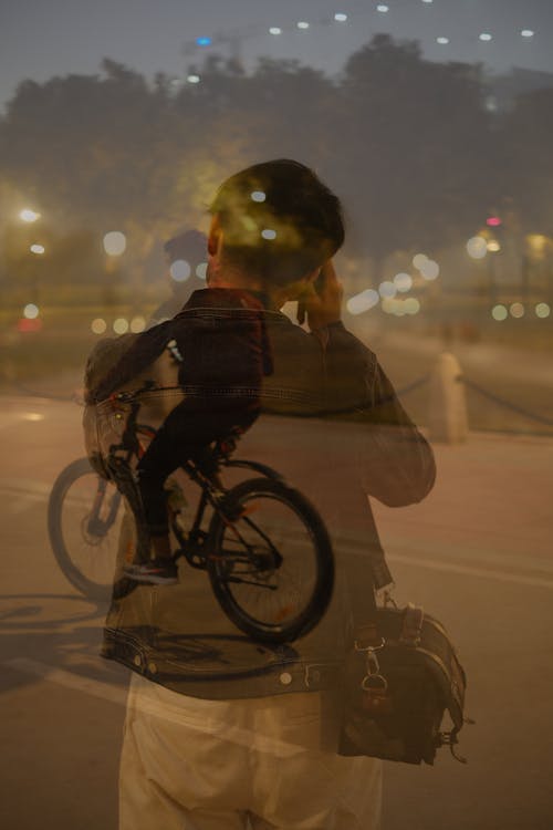 Man Riding a Bike Blurred with a Man Standing and Using His Cellphone