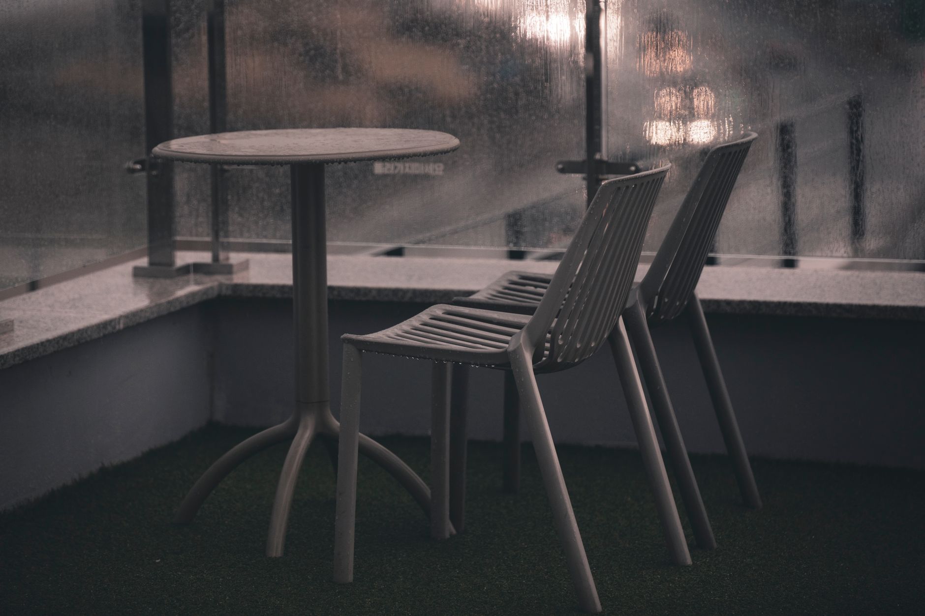 A minimalistic outdoor patio set featuring two chairs and a table in an urban balcony setting.