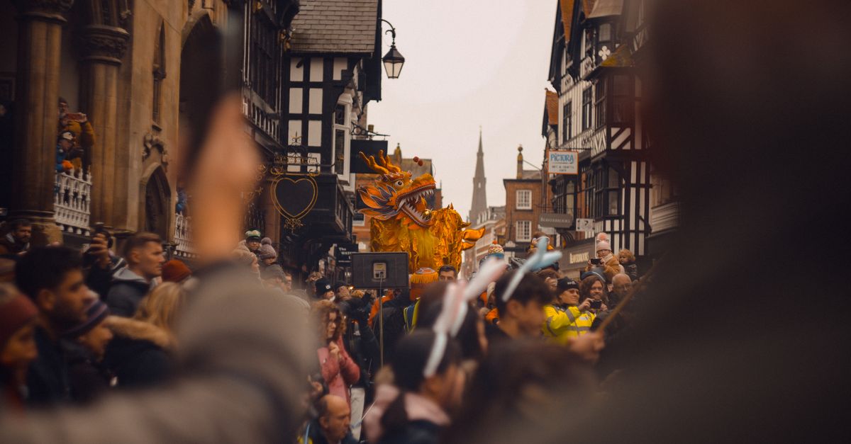 Vibrant festival parade with golden dragon in Chester, England.