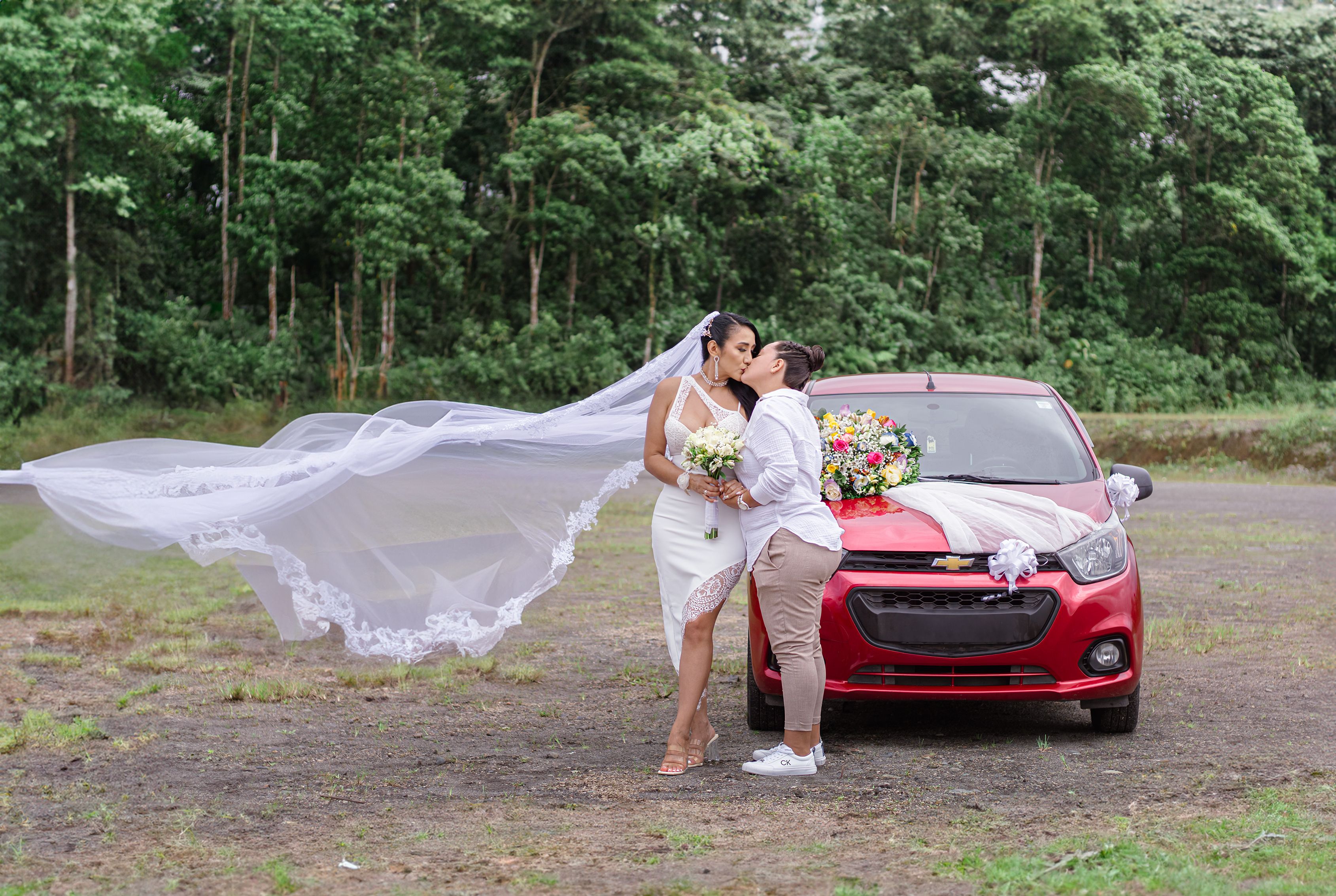 Newlyweds Kissing Next to a Decorated Car · Free Stock Photo