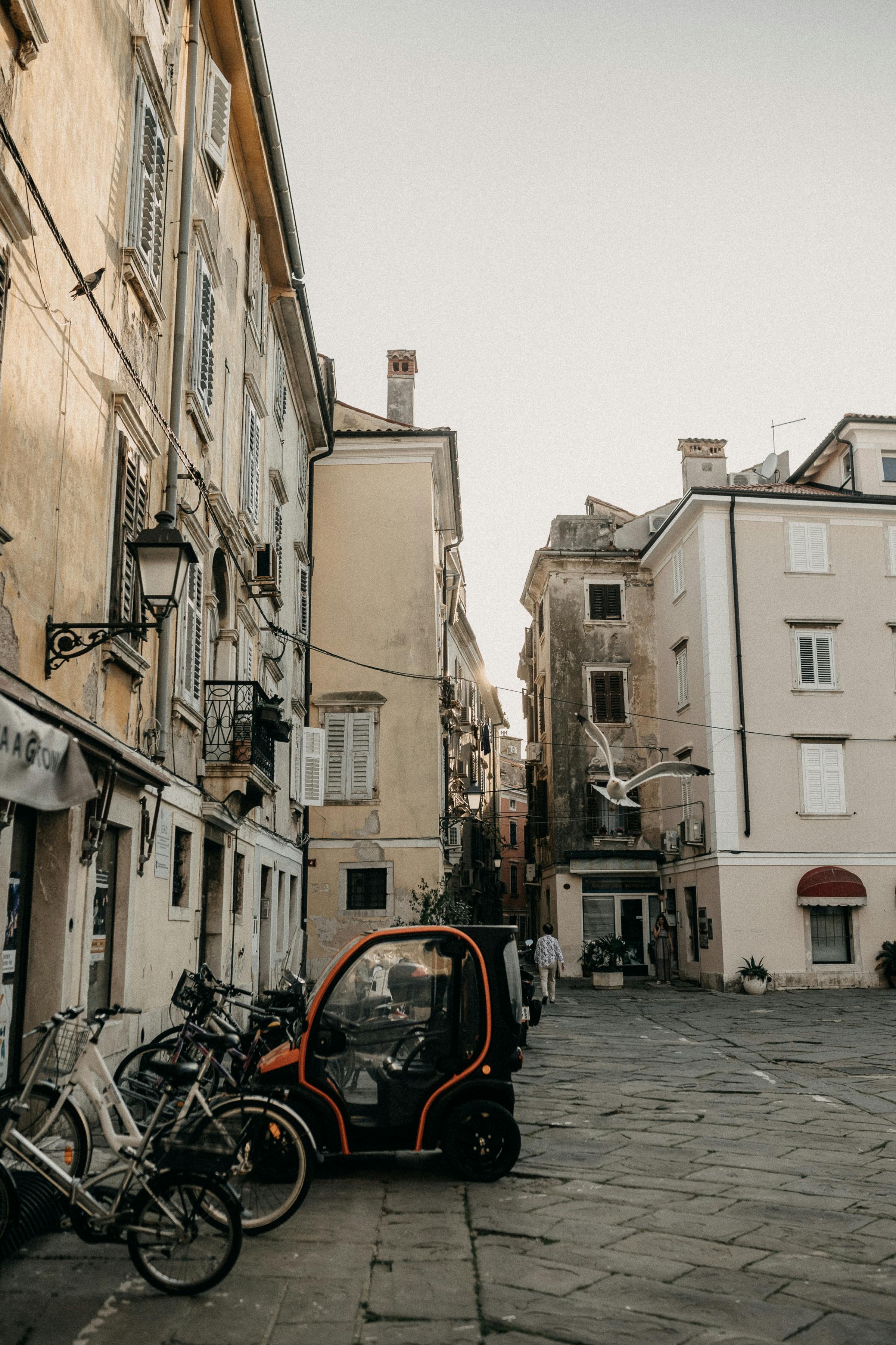 A picturesque view of a narrow street in Piran, Slovenia, featuring bicycles and quaint buildings.