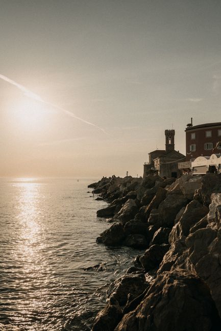The sun sets over the rocky coastline of Piran, Slovenia, offering a serene and picturesque view.