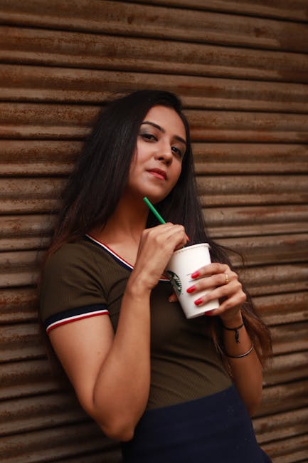 Woman sipping a drink outdoors, showcasing casual style and relaxation.