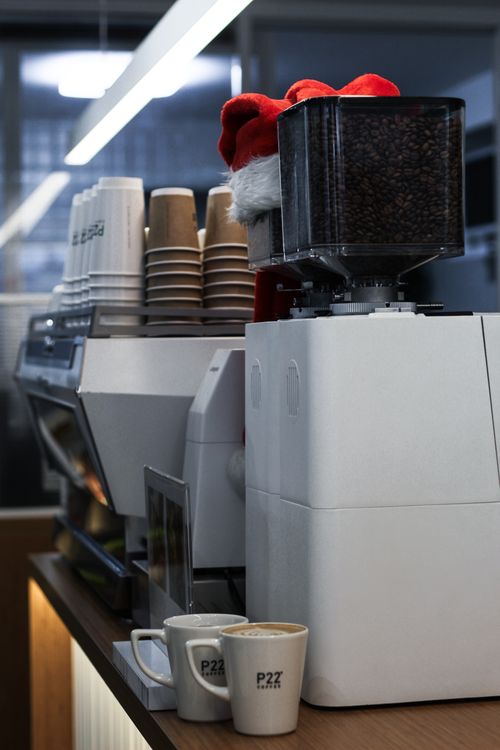 Free Close-up of a coffee machine in a café adorned with a festive Santa hat. Stock Photo