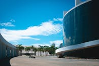 现代玻璃建筑在棕榈树和蓝天的映衬下，展示着城市建筑的风采