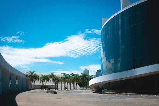 现代玻璃建筑在棕榈树和蓝天的映衬下，展示着城市建筑的风采