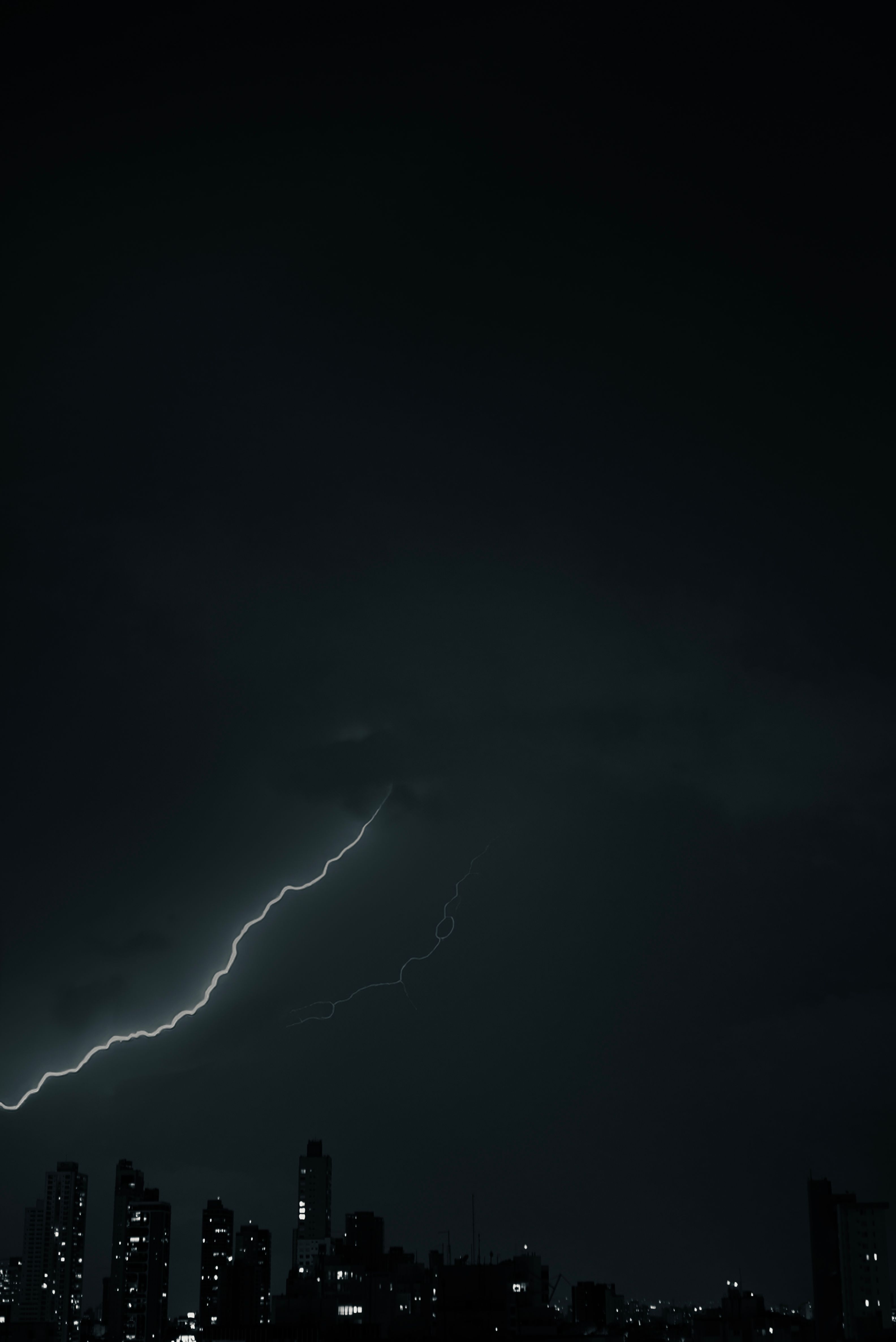 Fotomural Una vista dramática en monocromo del horizonte de la ciudad capturada por la noche con un impresionante rayo.
