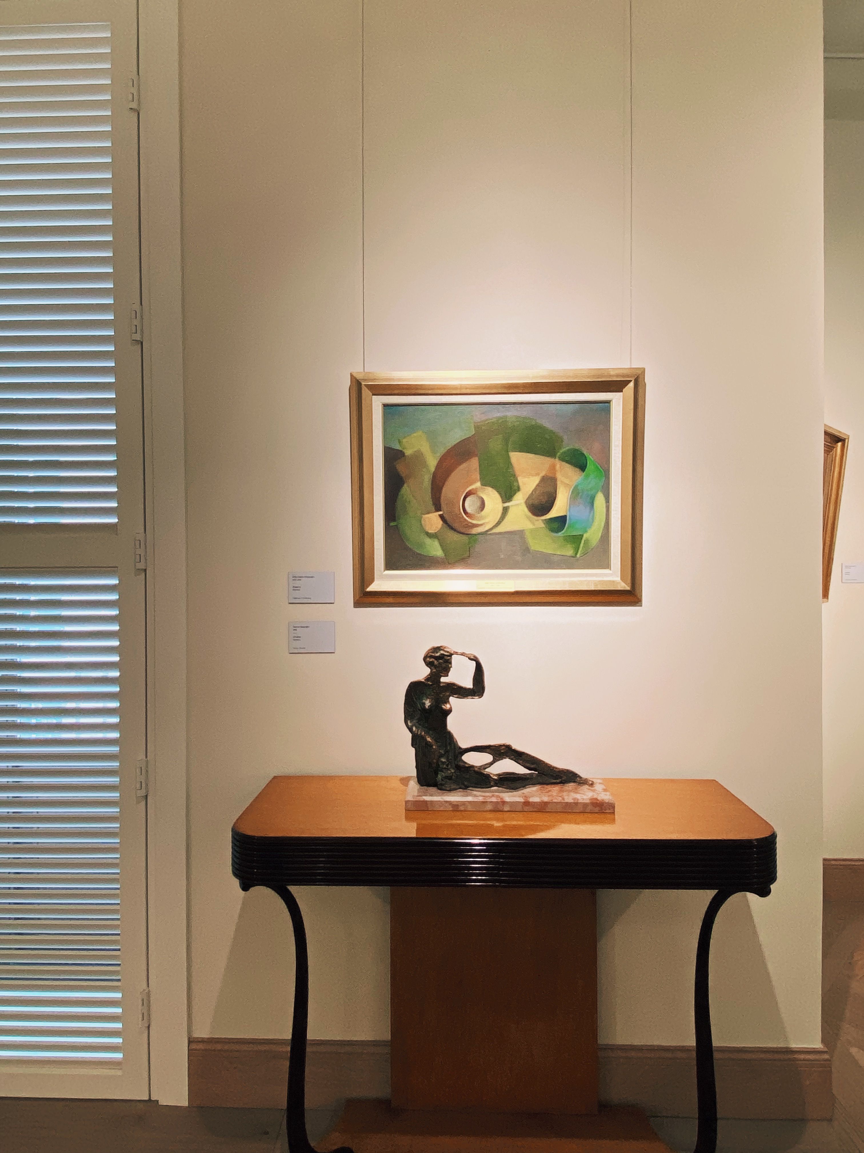 Free Artistic display featuring abstract painting and sculpture on wooden table in modern interior. Stock Photo