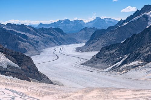 Free Majestic Aletsch Glacier, a UNESCO site, nestled in the Swiss Alps under a clear blue sky. Stock Photo