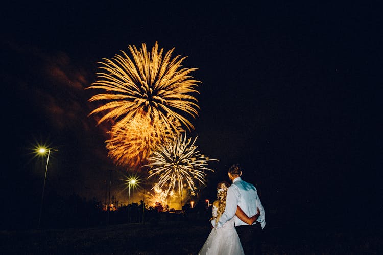 Bride And Groom Watching Fireworks In Night Sky