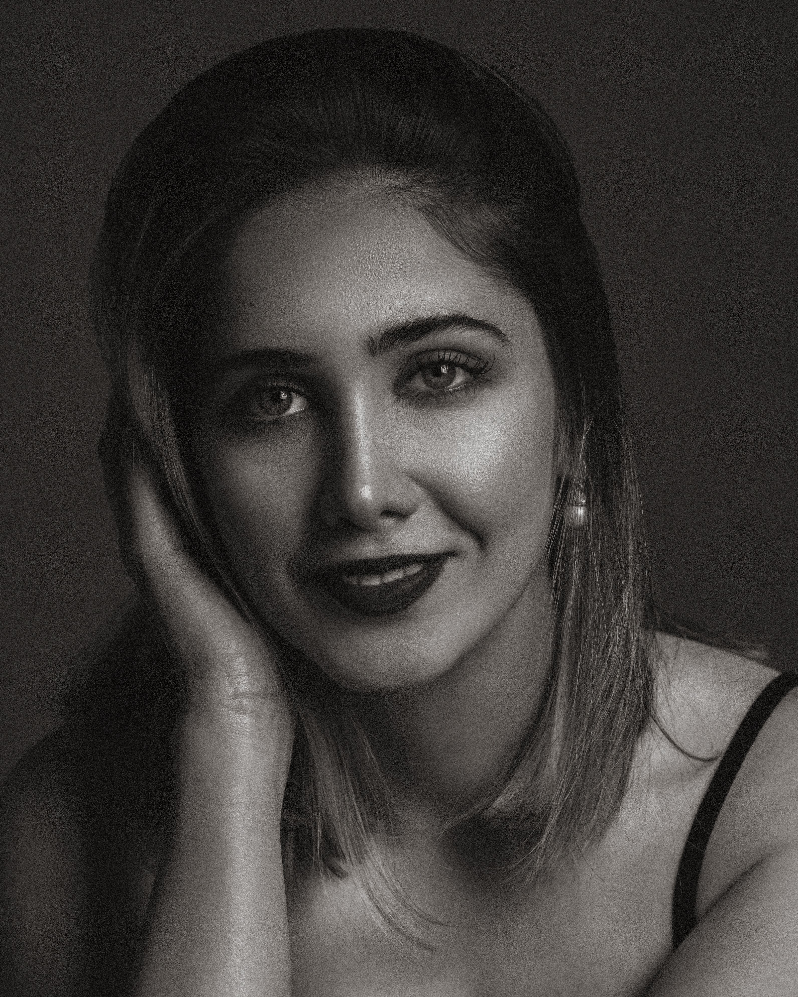 Striking monochrome portrait highlighting a woman's captivating smile and elegance.