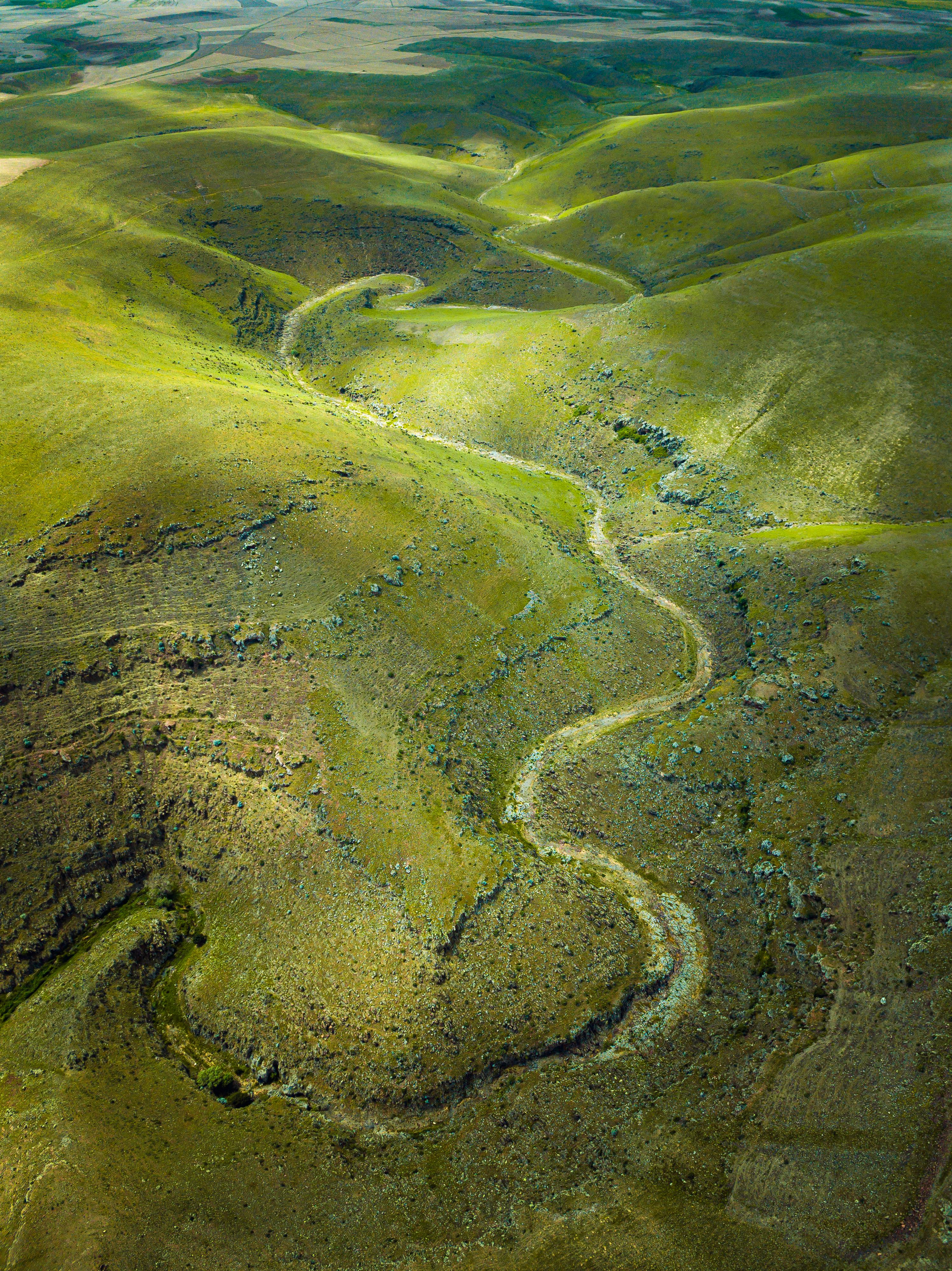 A breathtaking aerial shot of lush green hills and winding valleys under daylight.