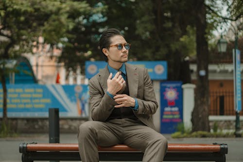 Man in Elegant Gray Suit and Blue Shirt Sitting on a Bench