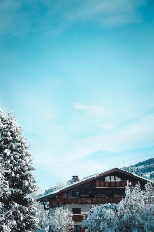 Free Charming wooden chalet surrounded by snow-covered trees in Megève, France. Stock Photo