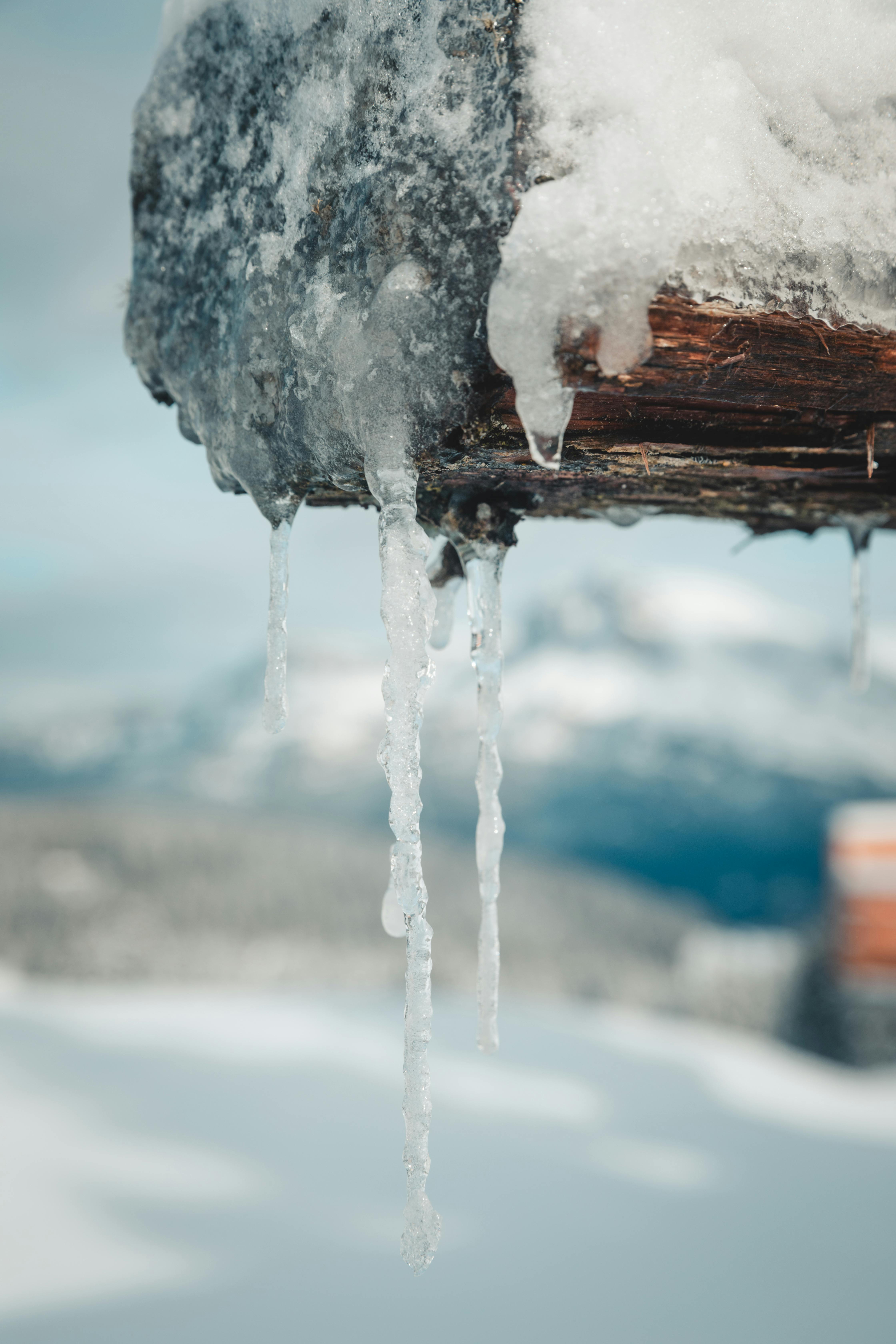 icicles hanging from a wooden post with snow in the background