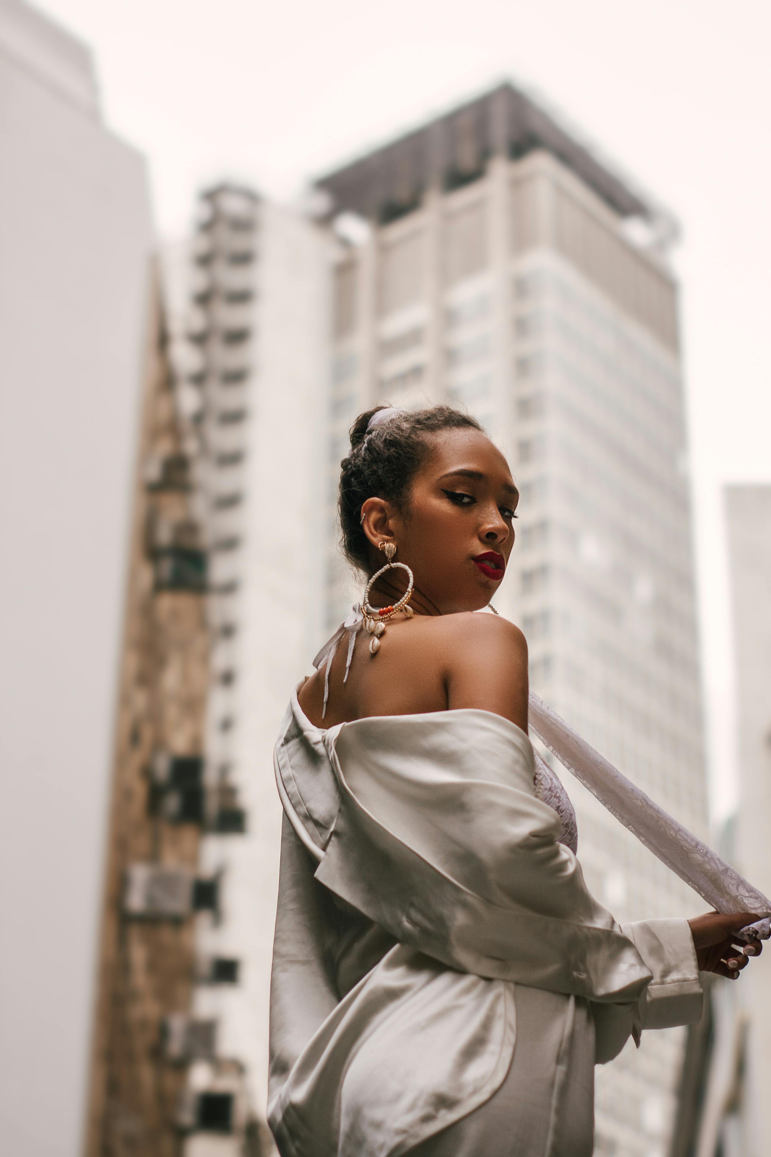 一位穿着缎面服装的时尚女士，在城市景观的背景下自信地摆着姿势