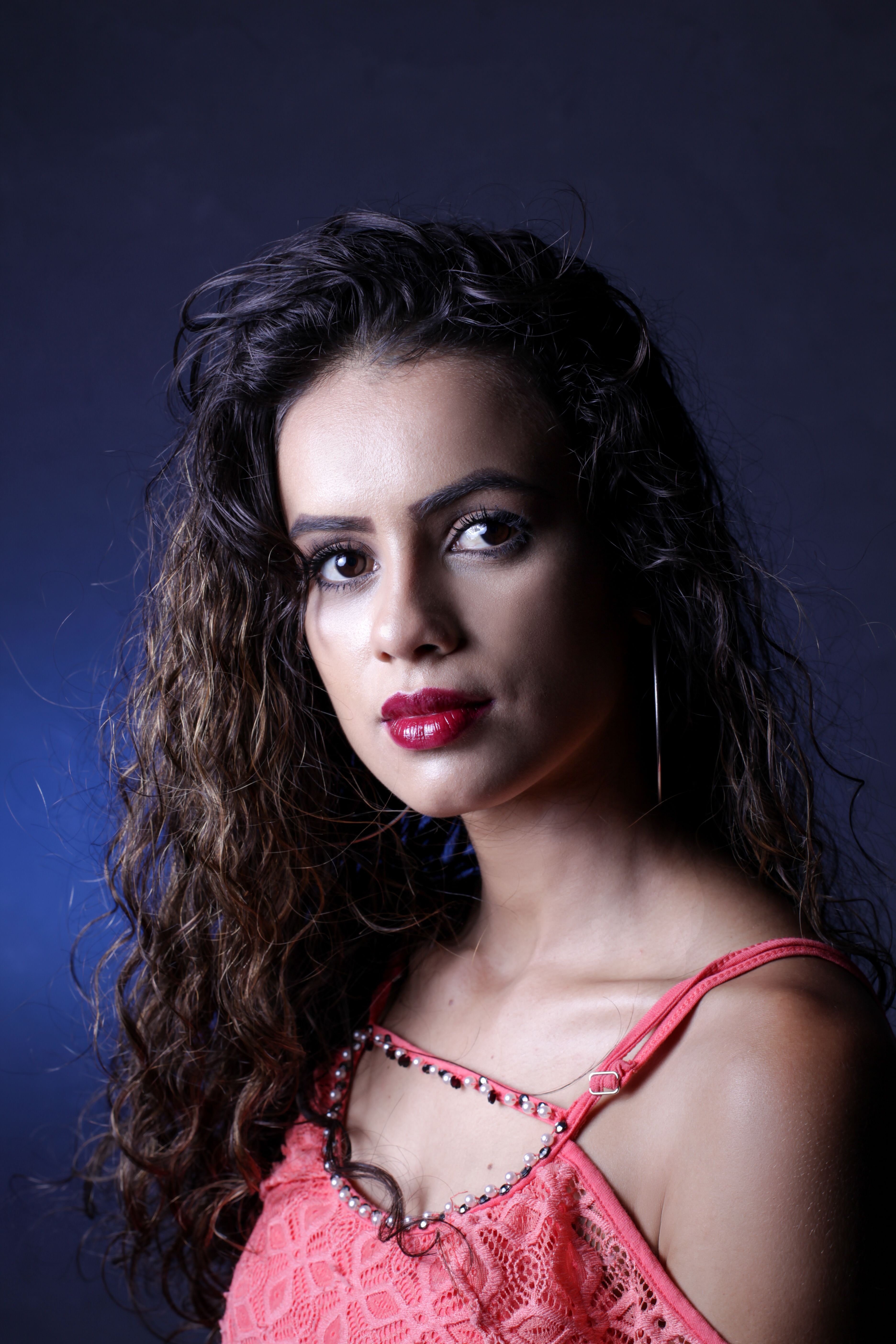 Close-up portrait of a young woman with long hair, vibrant red lipstick, and fashion style.