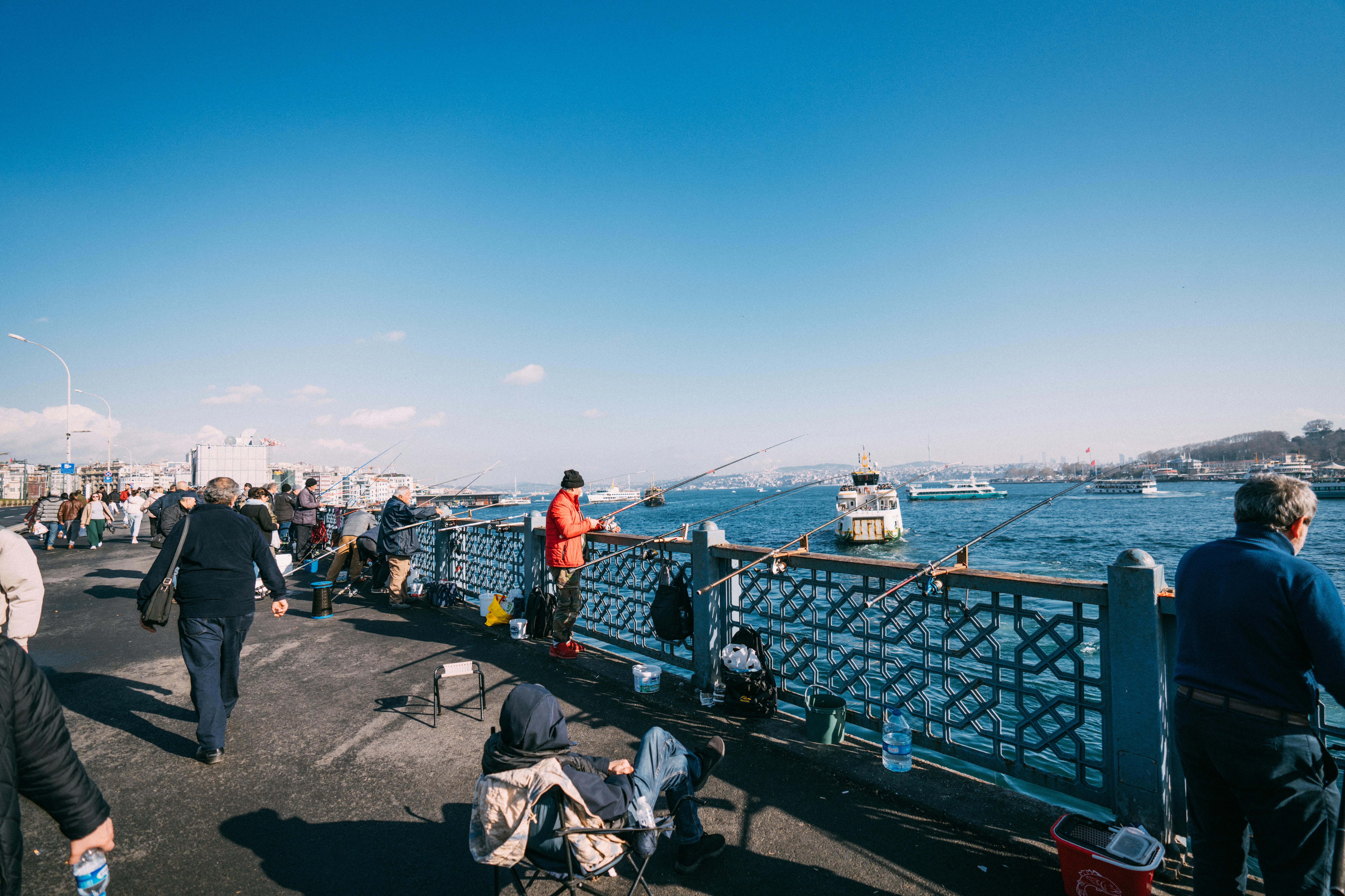 People enjoying recreational fishing on a city bridge with scenic urban water views.
