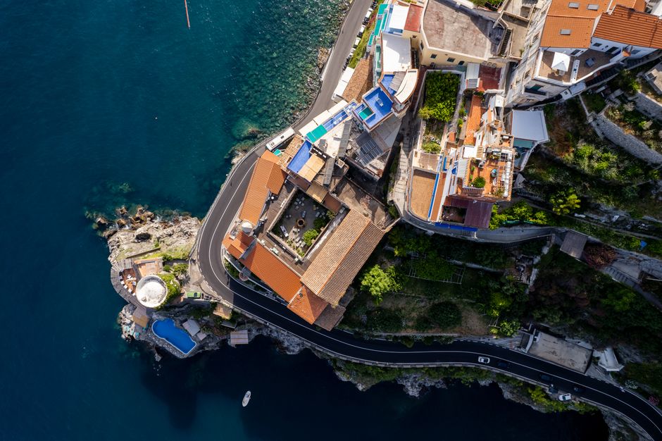 Drone shot of houses and roads along the Amalfi coast with stunning sea views.