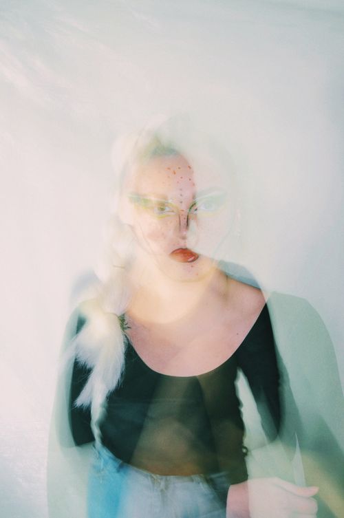 Free Creative portrait of a woman using blurred motion effect on a white background, adding an ethereal touch. Stock Photo