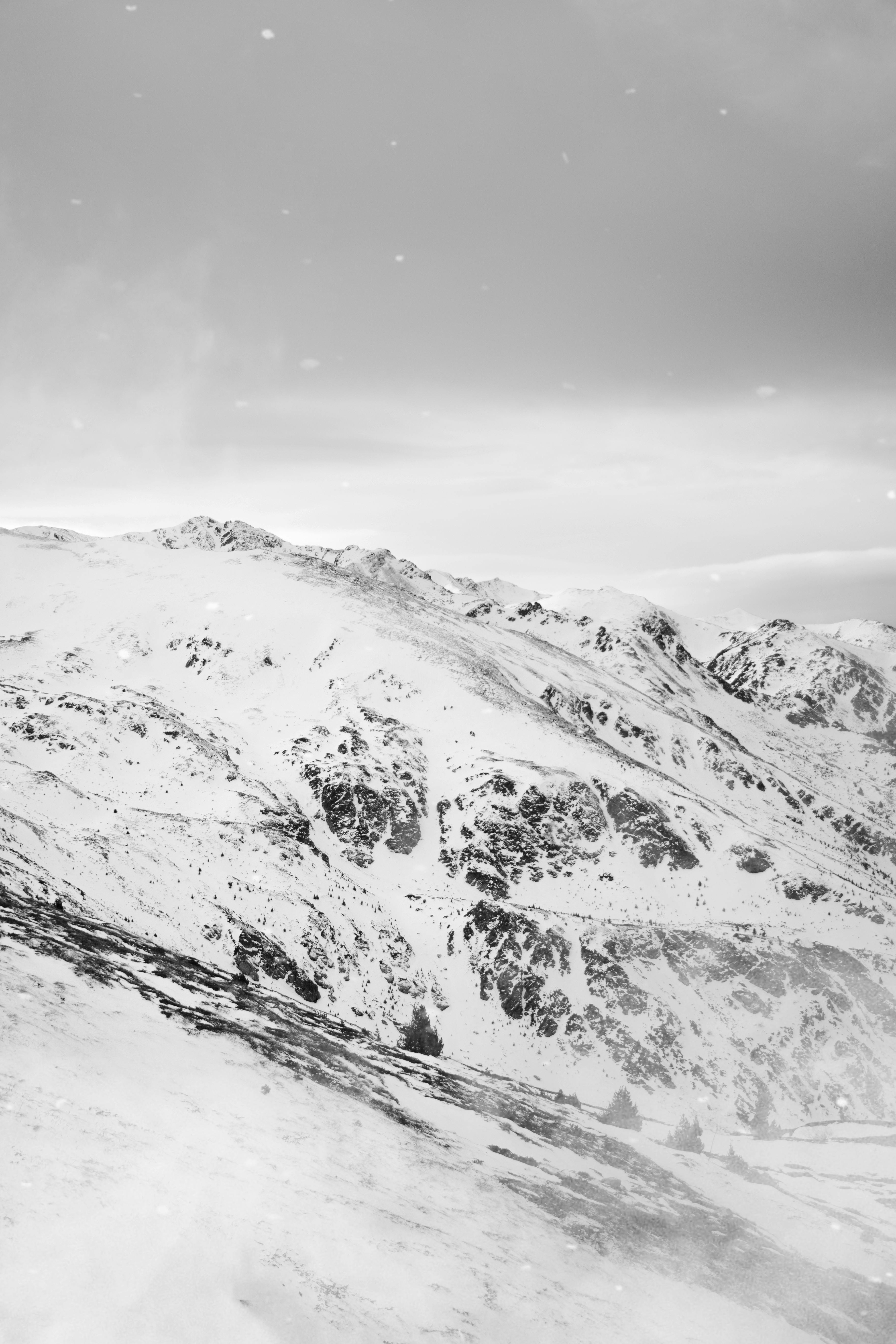 A serene black and white view of snow-covered mountains, capturing winter's tranquility.