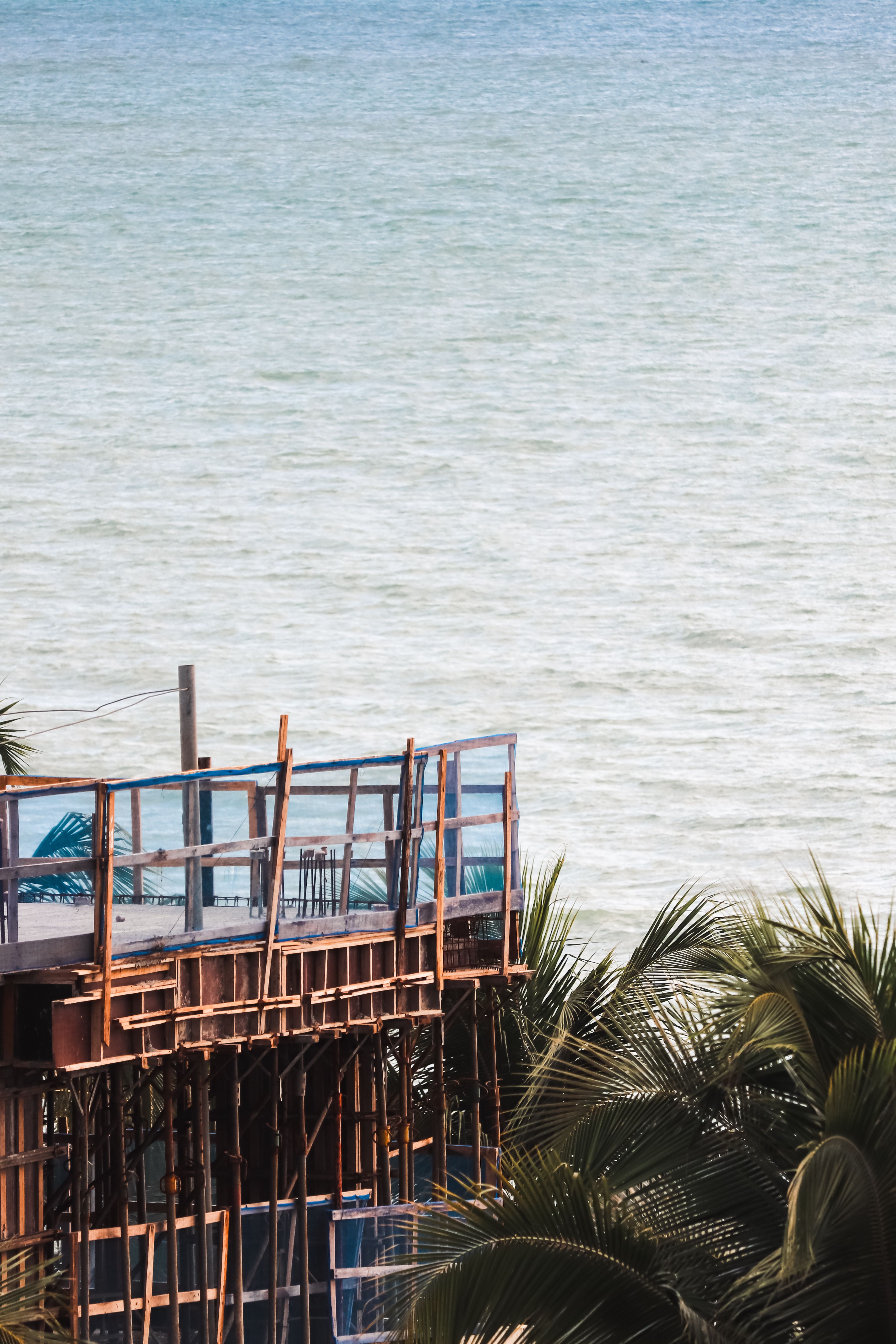 Wooden terrace overlooking ocean in PB, Brazil; serene atmosphere with palm trees.