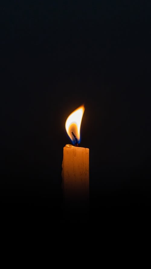 Wax Candle Burning in Darkness
