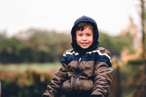 Free Boy Smiling and Wearing Hooded Jacket Outdoors Stock Photo