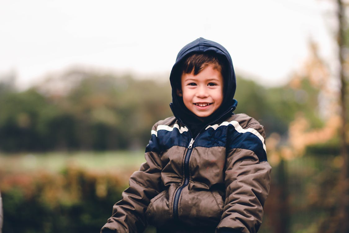 Boy Smiling and Wearing Hooded Jacket Outdoors