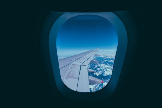 View of an aircraft wing and snowy mountains through a cabin window &mdash; photo by Francesco Ungaro on Pexels