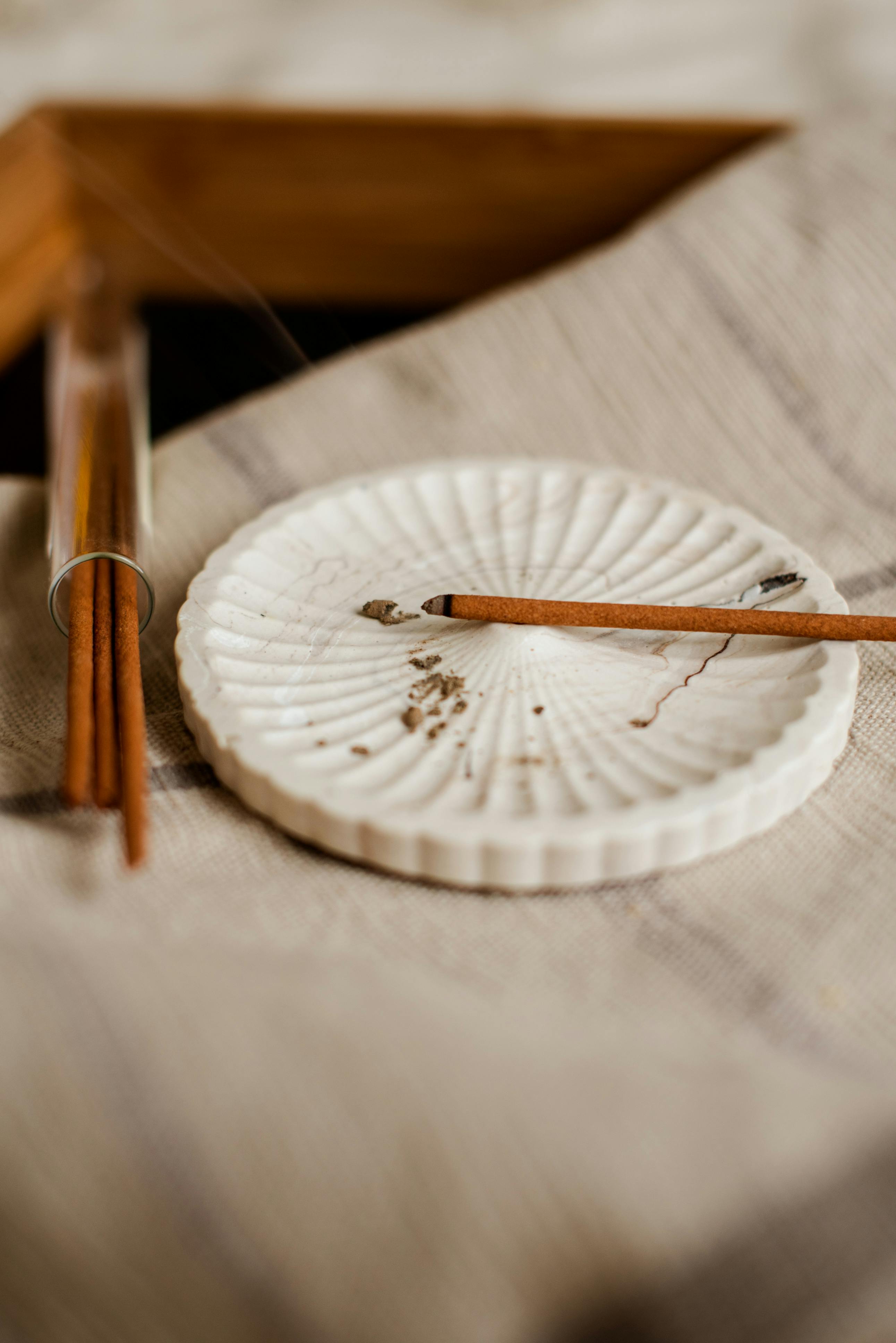 Detailed close-up of incense holder with wooden sticks on textured fabric for calming ambiance.
