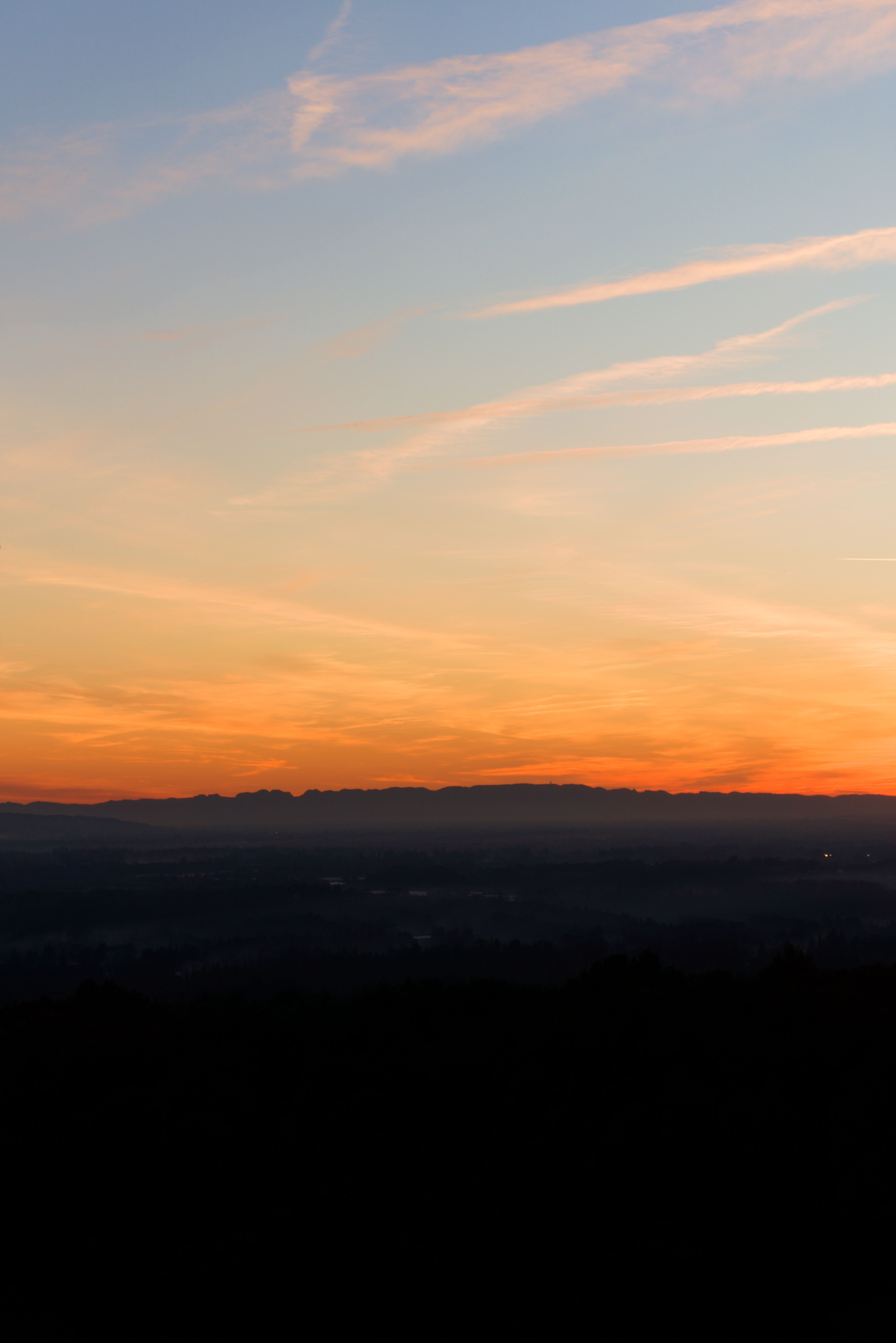 A stunning sunset scene with vibrant colors in a rural landscape and a silhouetted horizon.