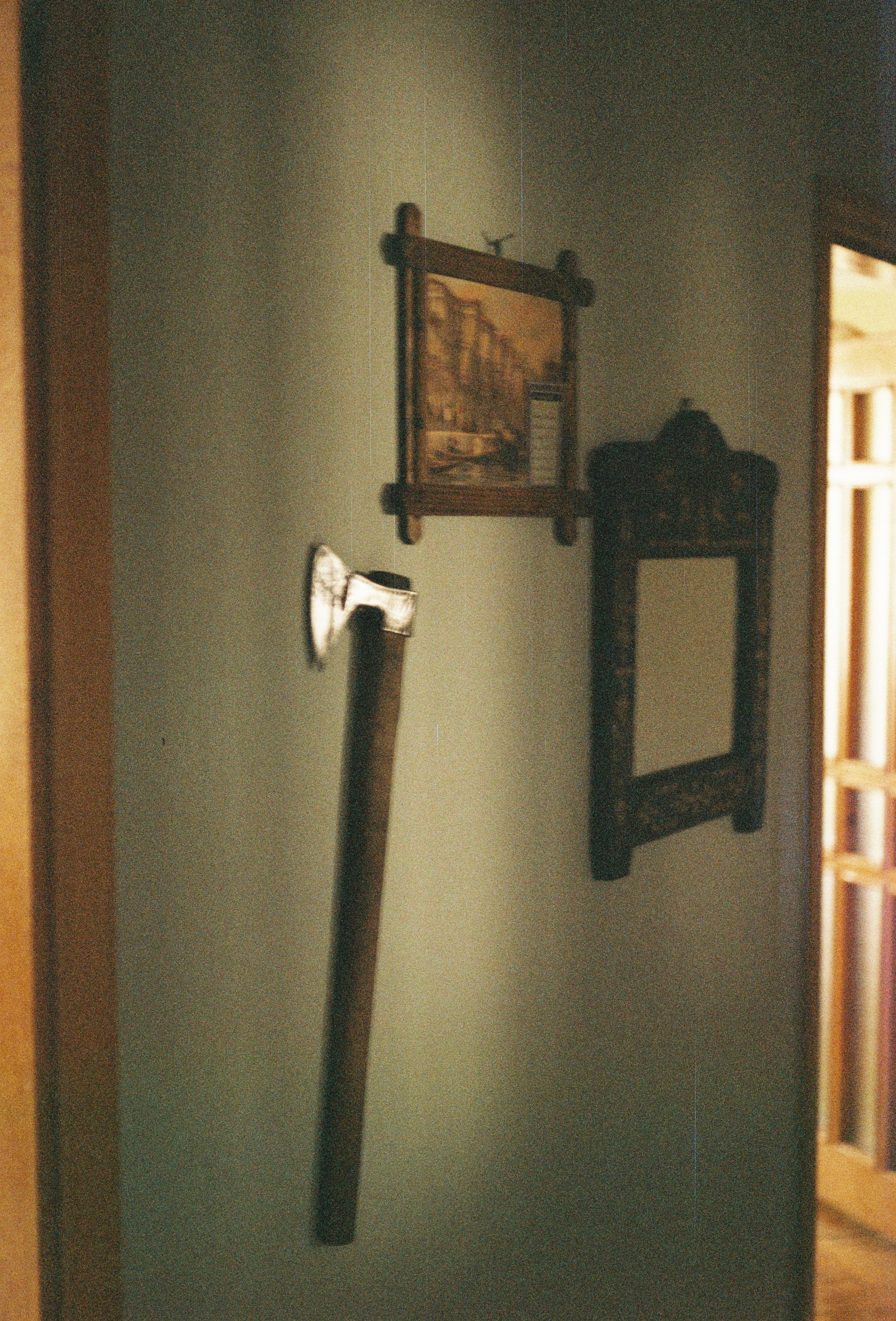 Vintage axe displayed on a home interior wall with a mirror and painting for rustic decor.