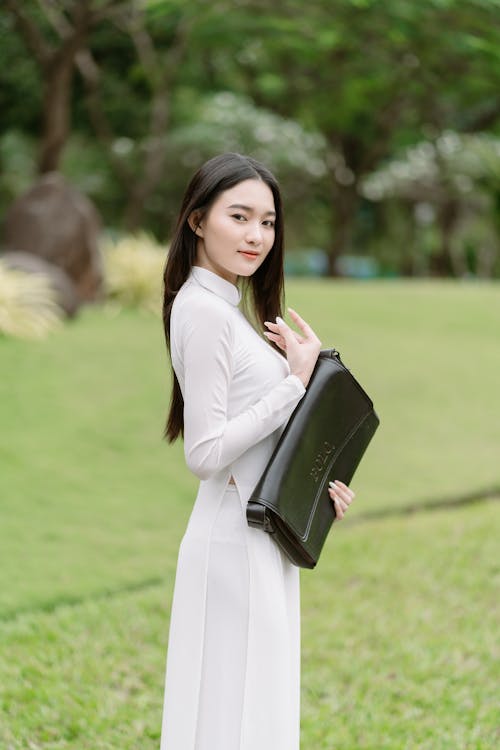 Woman in White Dress Standing with Bag