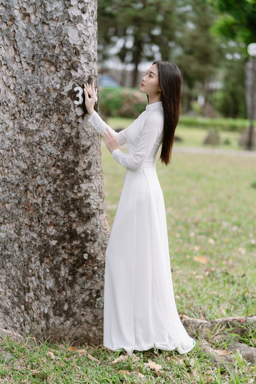 Woman in White Dress Standing by Tree in Park