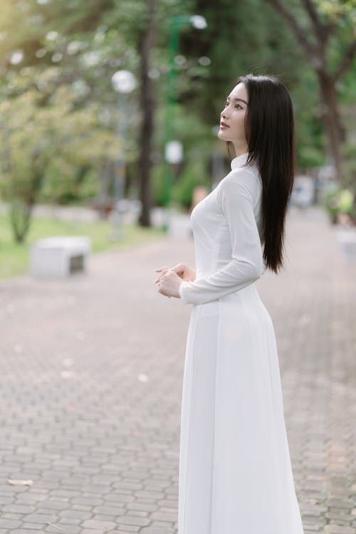 Model in a Long White Dress on a Walkway in the Park